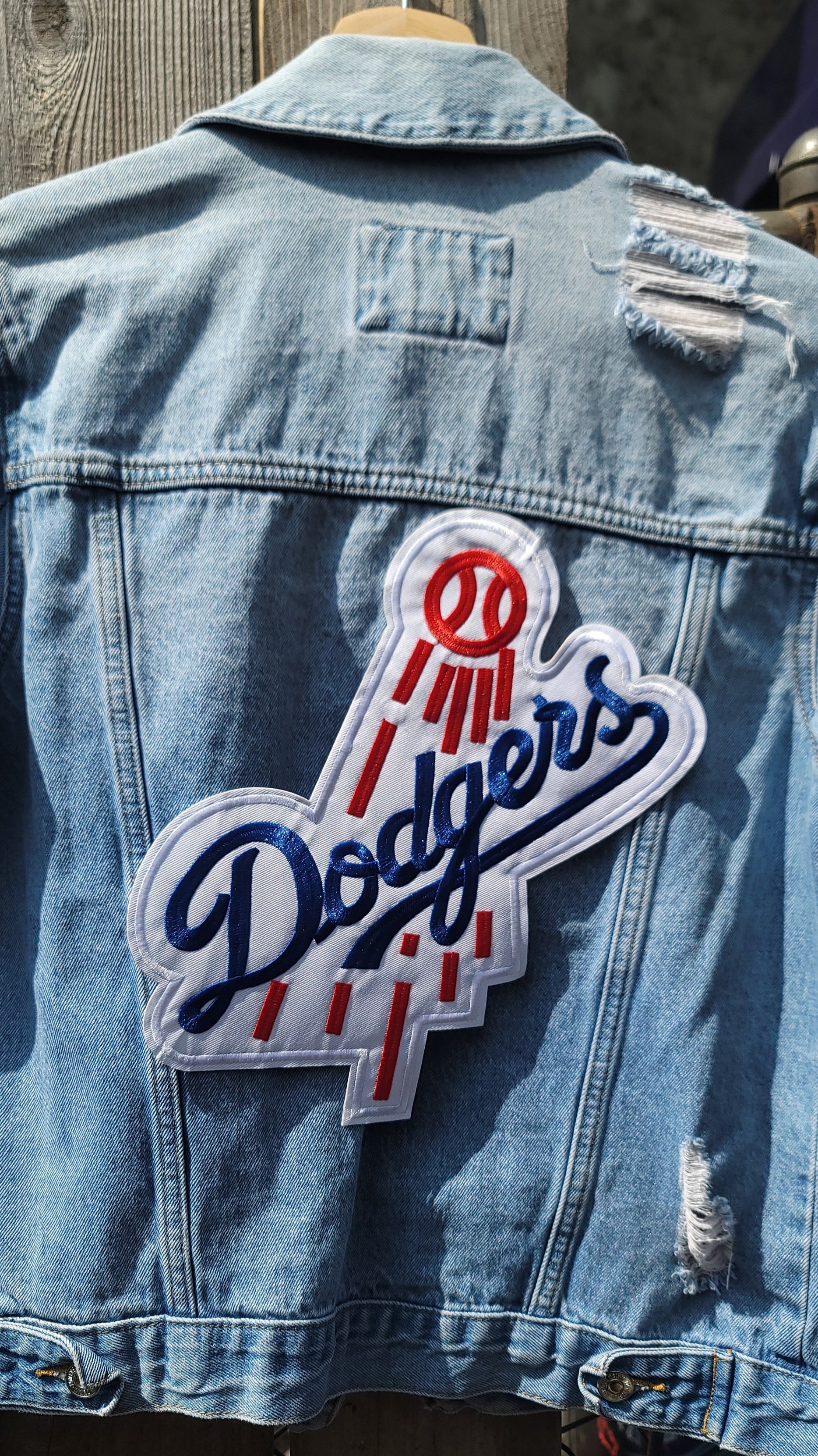 Denim jacket with a Dodgers logo patch on a wooden surface